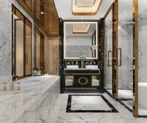 Modern luxury bathroom with white marble tiles, gold fittings, glass shower enclosure, and black marble vanity — a premium interior design by Maruthi Ceramics.